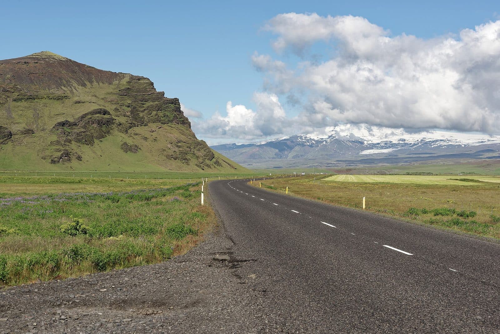 Iceland’s Route 1 curving through green meadows toward mountains in Mýrdalshreppur