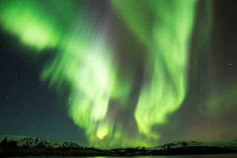 Dancing ribbons of green light paint the Arctic sky, as the Northern Lights shimmer above snowy peaks—a breathtaking display of nature’s magic and cosmic energy in motion.