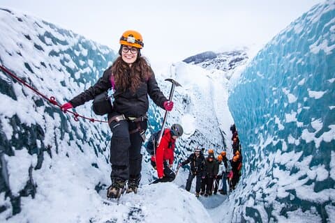 A woman smiles at the camera while holding a safety rope during a glacier hike in Skaftafell Nature Reserve, Iceland.