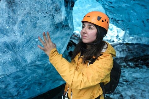 A woman touches the wall of an ice cave in Iceland.