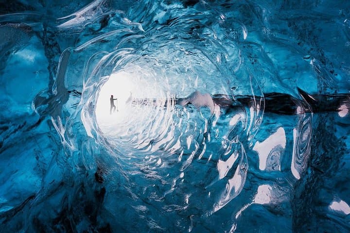 An ice cave forms inside Vatnajökull Glacier with smooth blue ice walls.