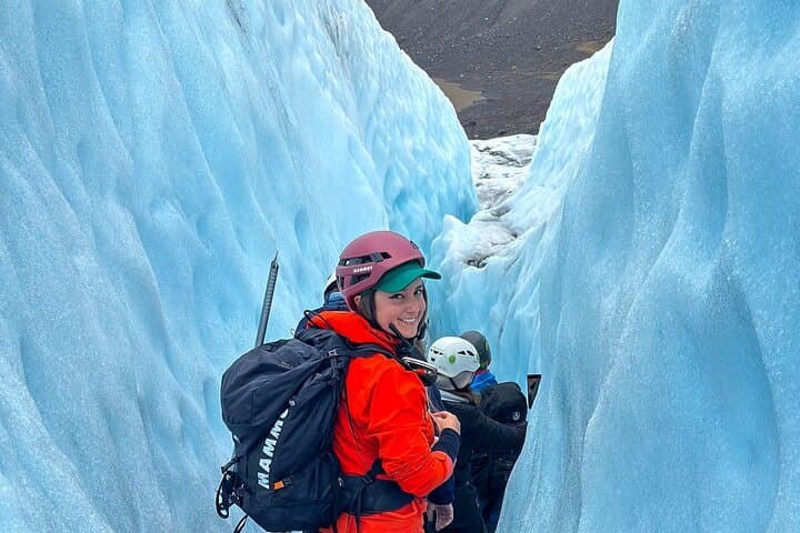 A woman smiles as her group walks through a narrow ice passage on a Skaftafell Glacier hike.