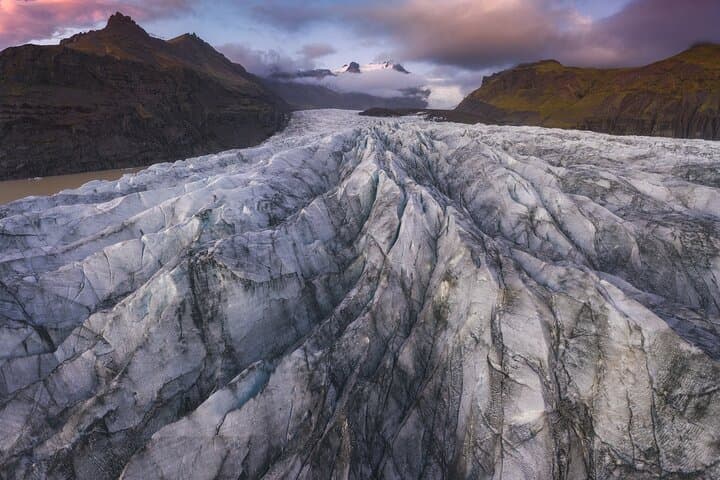 A glacier stretches across the land with thick ice, cracks, and uneven surfaces.