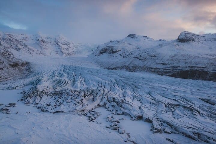 Solheimajokull Glacier is a vast, icy glacier with rugged surfaces and dark volcanic streaks.