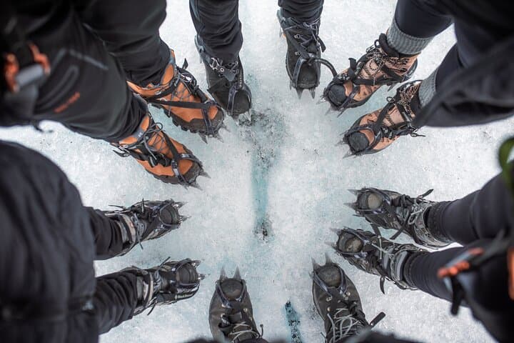 A group of travelers photographed their feet wearing crampons, forming a circle on the icy surface.