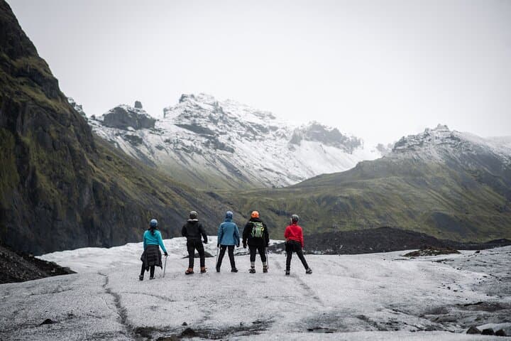 A group of travelers hikes across the icy terrain at Solheimajokull Glacier.