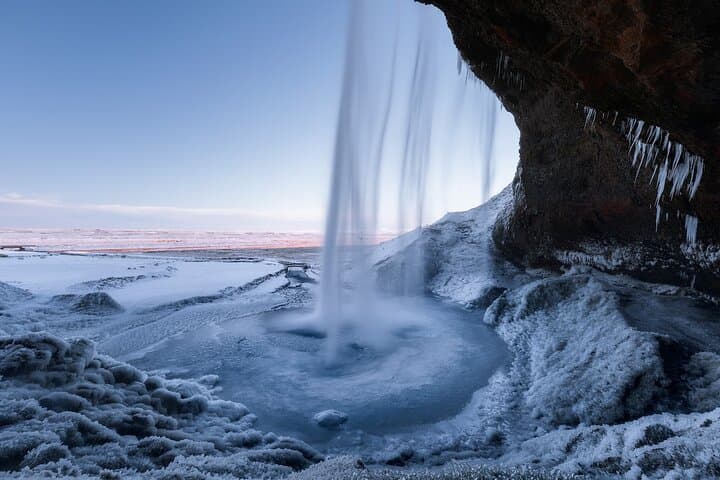Seljalandsfoss Waterfall falls in a close-up view, surrounded by a frozen winter landscape.